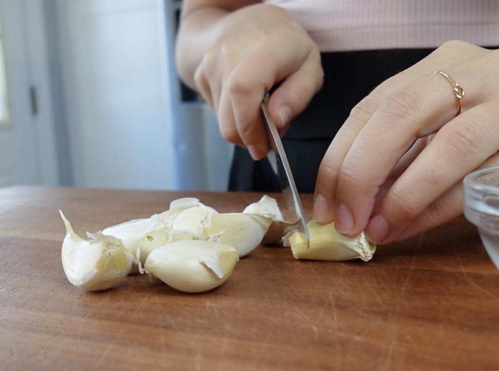 Chopping garlic on a wood cutting board.